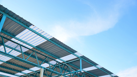Steel frame structure of metal sheet roof with blue sky and white clouds.の写真素材