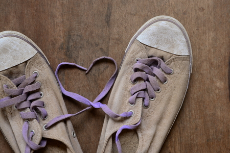 Heart shape made with laces of old  sneakers on wooden floor.の写真素材