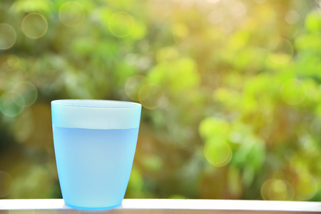 Blue plastic cup with water inside and blurred bokeh backgroundの写真素材