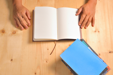 Human hands  open blank notebook on the wooden table.の写真素材