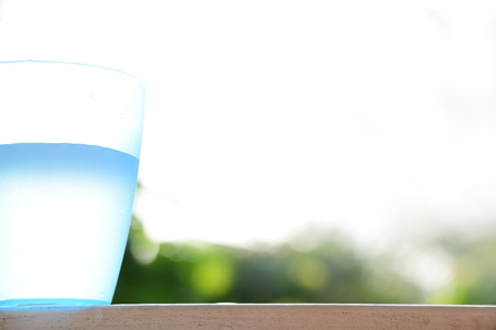 Blue plastic cup with water inside on blurred nature  background.の写真素材