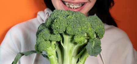Woman's mouth with broccoli between big white teethの写真素材