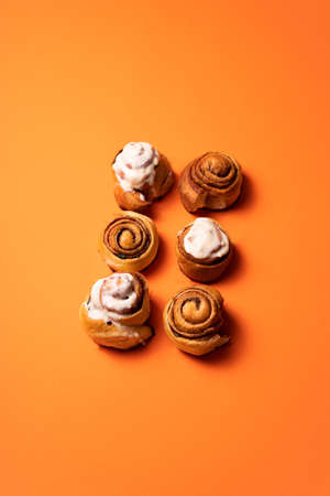 Freshly baked cinnamon buns on an orange background top view. patern. copy space