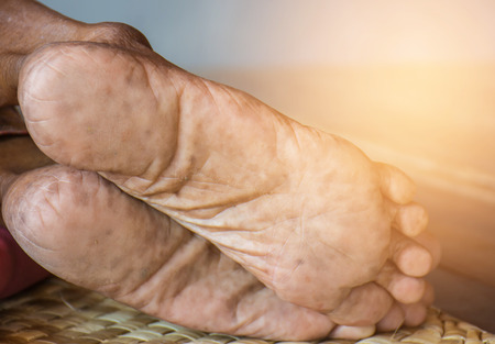 Feet of an old woman lying on the mat.