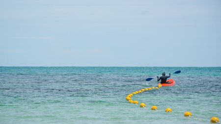 Men are paddling rubber boats and floating buoys in the sea. To create a safe zone for tourists to snorkel to see shallow coral reefs near the coast.Concepts of tourism and marine safety.の写真素材