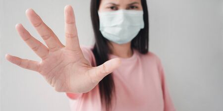 Thai woman wearing a face mask using a palm to show the stop of the covid virus outbreak. Concepts of virus and germ prevention Including the problem of air pollution.の写真素材