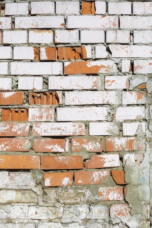 Texture of old brick wall. Dumps paint and plaster, broken bricks. Bright sunlightの写真素材