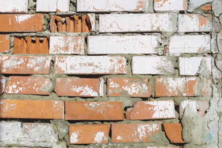 Texture of old brick wall. Dumps paint and plaster, broken bricks. Bright sunlightの写真素材