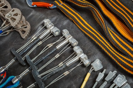 Equipment for mountaineering and rock climbing on a black waterproof fabric. Carabiners and slings,...
