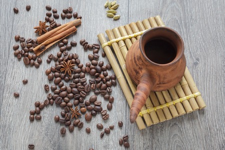 Coffee beans and spices on a wooden table. Clay forearm on a stand of bamboo.の写真素材