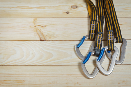 Equipment for mountaineering and rock climbing. On a wooden surface, pine boards. Slings with carabinersの写真素材
