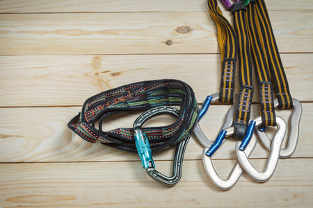 Equipment for mountaineering and rock climbing. On a wooden surface, pine boards. Slings with carabinersの写真素材