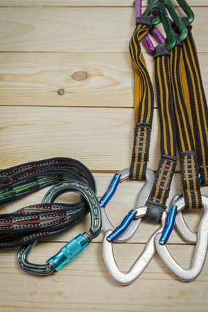 Equipment for mountaineering and rock climbing. On a wooden surface, pine boards. Slings with carabinersの写真素材