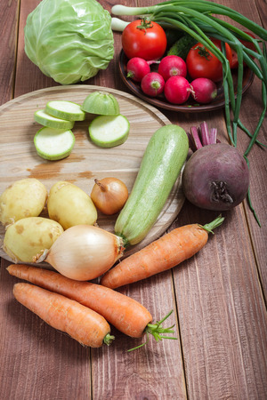Vegetarian food. Vegetables prepared for a meal on a wooden table. Round wooden board for cuttingの写真素材