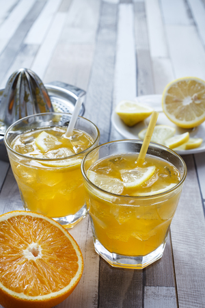 The cooled drink with fresh lemon and orange. On the table two glasses with a drink and fresh fruitの写真素材