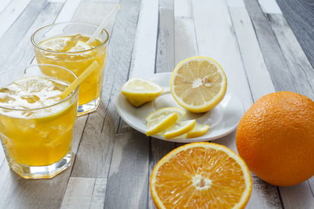The cooled drink with fresh lemon and orange. On the table two glasses with a drink and fresh fruitの写真素材