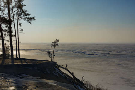 Frozen shore of the Kiev Sea at sunset. Fragments of ice, pine trees in the foreground. colorful cloud landscape. Reflections of naldu symmetry. Nature, climate change. panoramic viewの写真素材