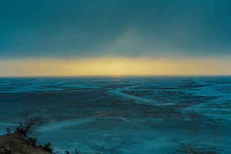 Frozen shore of the Kiev Sea at sunset. colorful cloud landscape. Sun reflections on ice. Nature, climate change. panoramic viewの写真素材