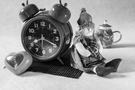 Alarm clock and decorative elements on a bamboo table. Rag doll and ceramic heartの写真素材