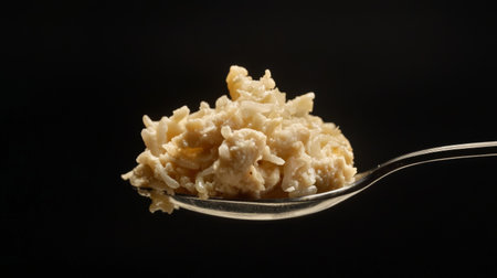 A detailed close-up image of creamy oatmeal balanced on a spoon, showcasing its inviting texture and natural colors, ideal for healthy breakfast themes and culinary presentations.の素材