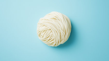 A visually appealing image of a nest of uncooked spaghetti noodles resting on a bright blue background, perfect for culinary projects and food-related themes.の素材