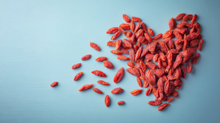 This creative arrangement of dried goji berries forms a heart shape against a blue background, symbolizing health, love, and the benefits of nutritious snacking.の素材