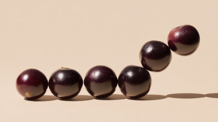 A captivating arrangement of dark shiny grapes on a soft beige background, highlighting their vibrant color and shadows, perfect for food or lifestyle themes.の素材