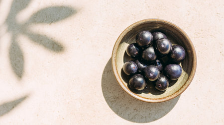 A charming display of fresh blueberries in a rustic bowl, set on a light stone surface. Soft leaf shadows create a serene and inviting atmosphere, perfect for healthy living.の素材