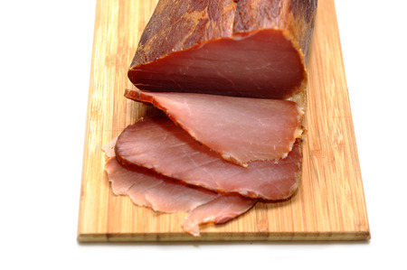 Sliced prosciutto on a wooden board isolated on white の写真素材