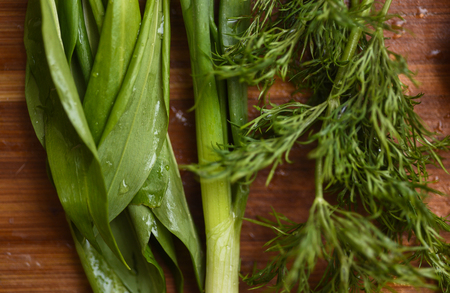 Heap of green onion, dill and ramsons on rustic wooden table