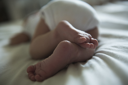 Small foots of newborn baby. Newborn baby is liyng on white ground.の写真素材