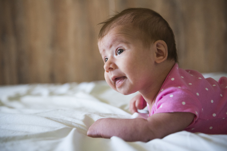 Newborn lying on stomach trying to hold her headの写真素材