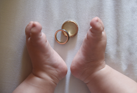 Feet of a newborn and his parents' wedding ringsの写真素材