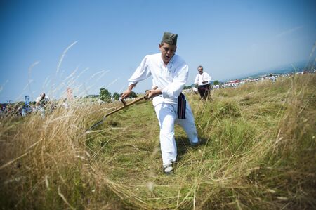 RAJAC, SERBIA - JULY 19, 2015: Mowing on Rajac mountain, traditional competiton in Central Serbia, near Ljig city, during which farmers in traditional clothes compete in mowing with scytheのeditorial素材