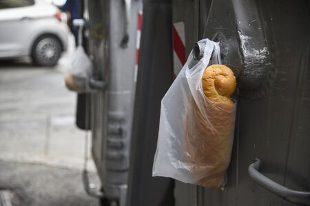 plastic white bag with bread in it, hang on metal container for garbage, left for homeless and...