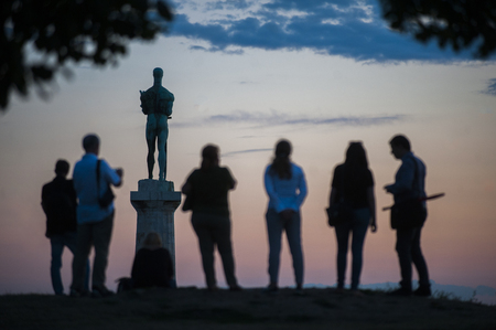 BELGRADE, SERBIA - AUGUST 18, 2015: Silhouettes of young people during sunset in Kalemedan park with the view of monument âThe Victorâ at fortress in Belgrade, Serbiaのeditorial素材