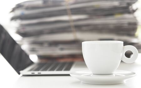 Take a break concept picture, pile of newspapers, opeed laptop and cup of coffee on the table