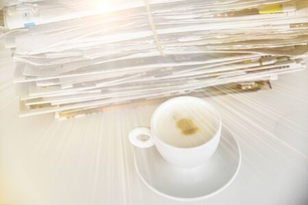 Take a break concept picture, pile of newspapers and cup of coffee on the table with a sunshineの写真素材