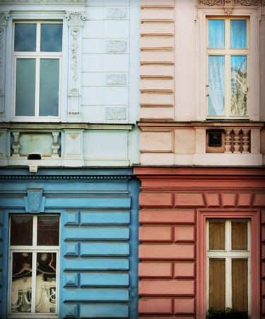 Striking historical facade detail in four colors: pastel blue, pink, deep blue, and red. Features ornate stucco, windows, and symmetry. Perfect background for travel, culture, urban life, and color contrast concepts.の写真素材