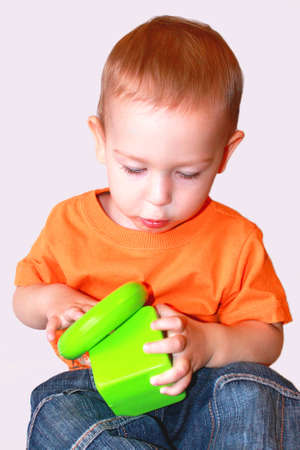 Baby in orange shirt playing with toys.の写真素材