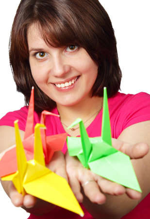 Portrait of a beautiful smiling brunette holding paper crane isolated on white backgroundの写真素材