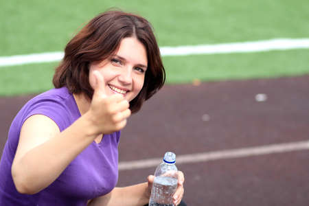 Beautiful Fitness Woman with Bottle of Water and Thumb Upの写真素材