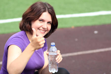 Beautiful Fitness Woman with Bottle of Water and Thumb Upの写真素材