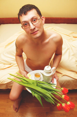 Breakfast in bed. Romantic young man with tray and flowersの写真素材