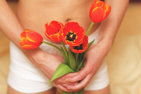 Romantic young man with flowers. Focus on flowers.の写真素材