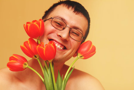 Romantic smiling young man with flowersの写真素材