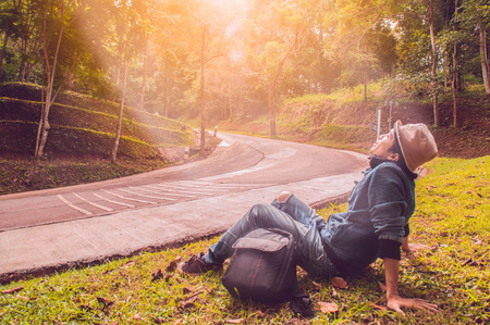 Happy man traveler sitting on green lawn and relaxing at sunset time,travel conceptの写真素材