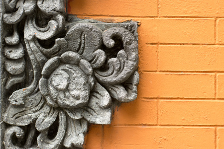 Grey cement flower decoration ornament on orange brick wallの写真素材