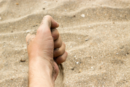 Hand holding sand running down at the beachの写真素材