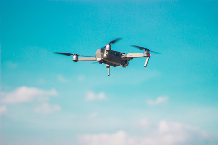 Flying quadrocopter in a blue sky making movie. Photo and video.